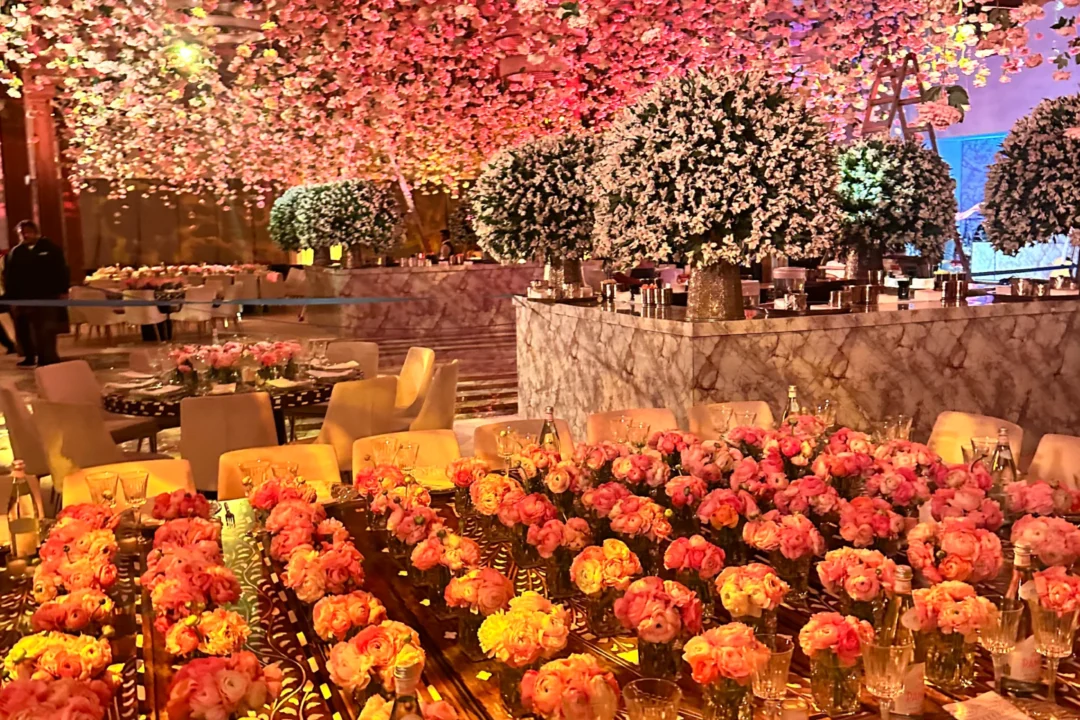 A beautifully decorated banquet space with tables adorned in vibrant floral arrangements and an enchanting overhead display of blossoms.